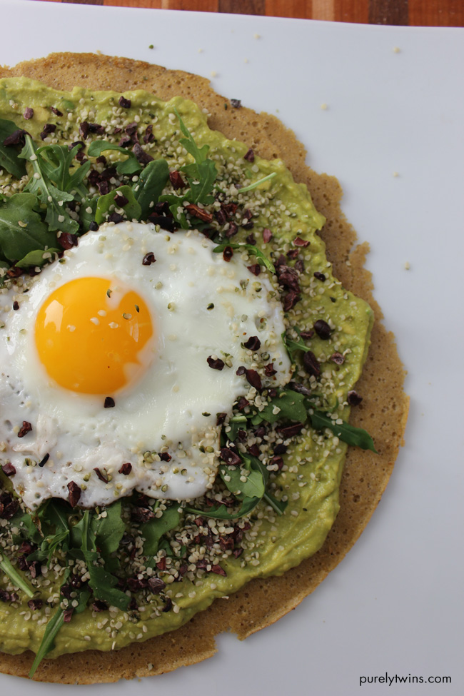 Gluten-free, grain-free breakfast pizza that will fuel you for your busy day ahead. Quick and healthy breakfast pizza. Made from real foods. A warm crust topped with creamy avocado cream, topped with spicy peppery-mustardy arugula, savory hemp seeds, runny egg and cacao nibs for fun.