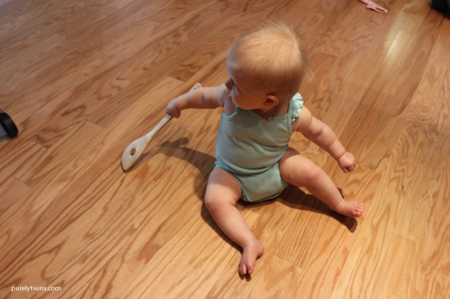 Playing with favorite baby toy. A wooden spoon to hit the floor with to make noise. \\purelytwins.com