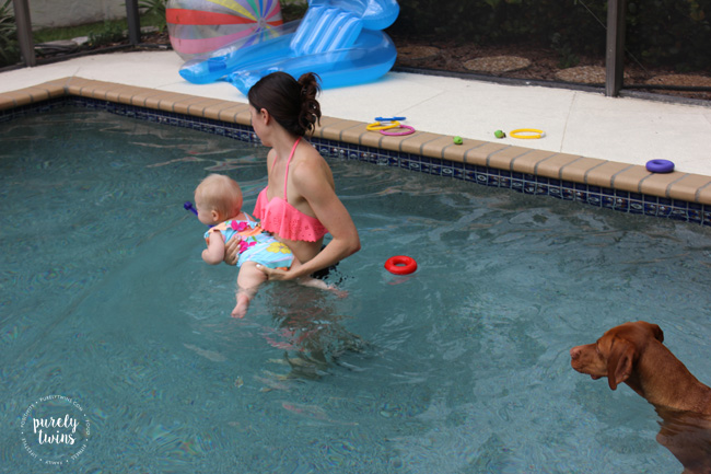 mom-holding-one-year-old-swimming-in-pool-purelytwins
