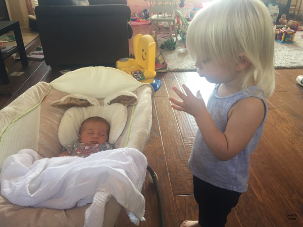 2 year old big sister talking to newborn baby sister